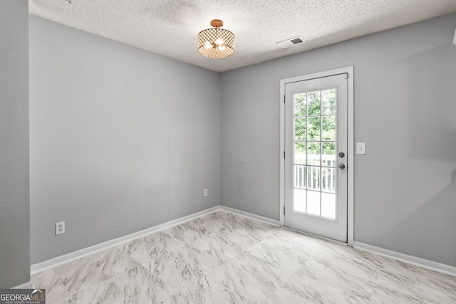interior space featuring a textured ceiling, visible vents, and baseboards