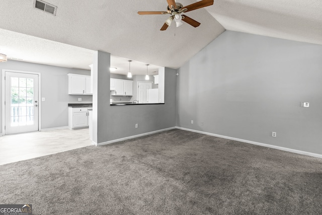 unfurnished living room featuring a textured ceiling, ceiling fan, visible vents, and light carpet