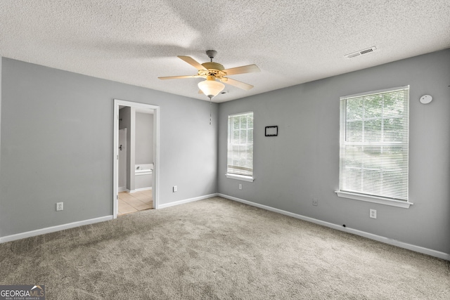 unfurnished bedroom featuring visible vents, baseboards, carpet flooring, ceiling fan, and ensuite bathroom