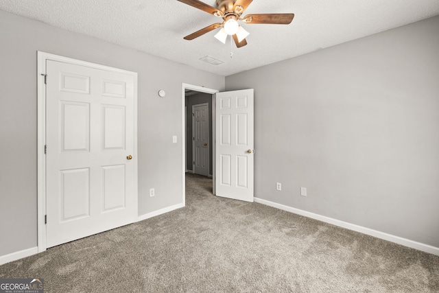 unfurnished bedroom with a textured ceiling, carpet flooring, baseboards, and ceiling fan