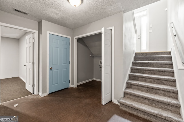 staircase featuring wood finished floors, visible vents, and a textured ceiling
