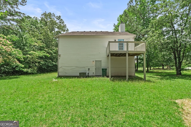 back of property featuring a wooden deck, central air condition unit, a lawn, and a chimney
