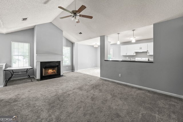 unfurnished living room with a textured ceiling, vaulted ceiling, visible vents, carpet, and ceiling fan
