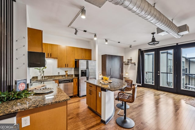 5300 Peachtree Rd Unit 3601, Atlanta, GA 30341 - kitchen featuring appliances with stainless steel finishes, a kitchen bar, brown cabinetry, french doors, and light wood-style flooring