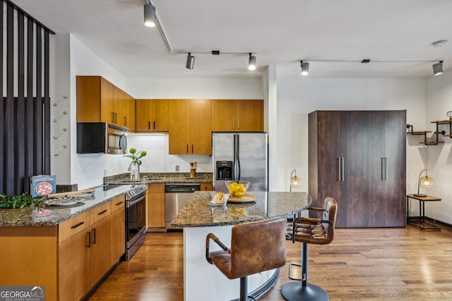 5300 Peachtree Rd Unit 3601, Atlanta, GA 30341 - kitchen featuring stainless steel appliances, wood finished floors, a kitchen bar, track lighting, and dark stone countertops