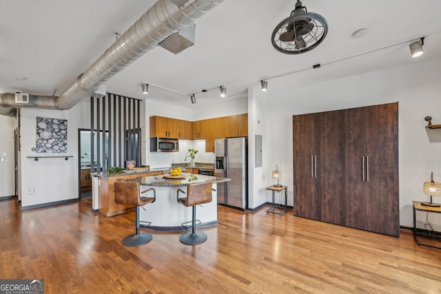 5300 Peachtree Rd Unit 3601, Atlanta, GA 30341 - kitchen with stainless steel appliances, a center island, light wood finished floors, a breakfast bar, and dark stone counters