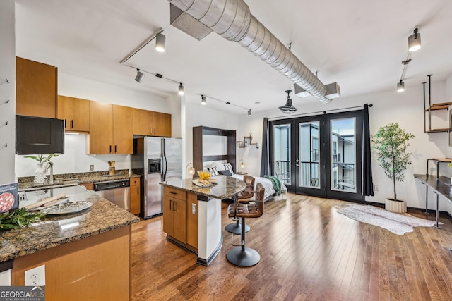5300 Peachtree Rd Unit 3601, Atlanta, GA 30341 - kitchen with stainless steel appliances, french doors, brown cabinets, a kitchen bar, and hardwood / wood-style flooring