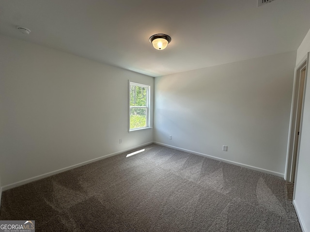 unfurnished room with baseboards and dark carpet