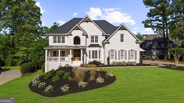 view of front of home featuring roof with shingles, a standing seam roof, a porch, metal roof, and a front yard
