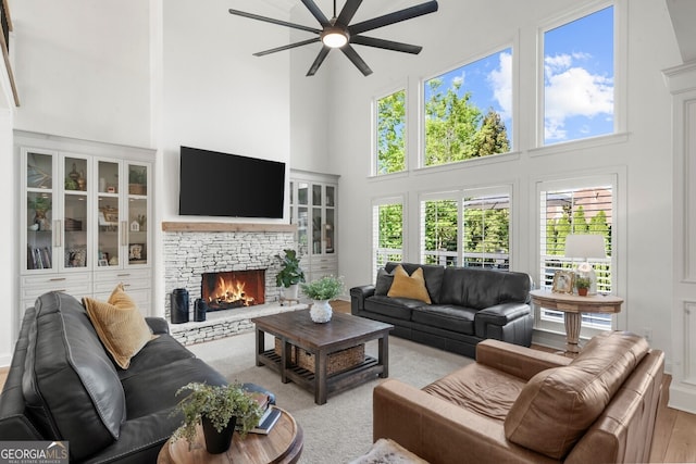 living room with a fireplace, a towering ceiling, and a ceiling fan