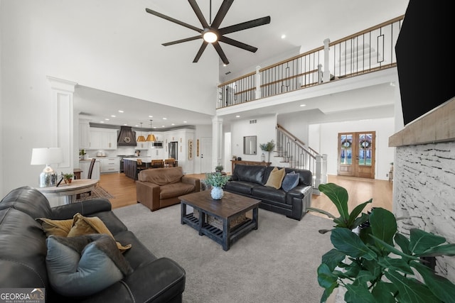 living area featuring stairs, ornate columns, ceiling fan, a high ceiling, and recessed lighting