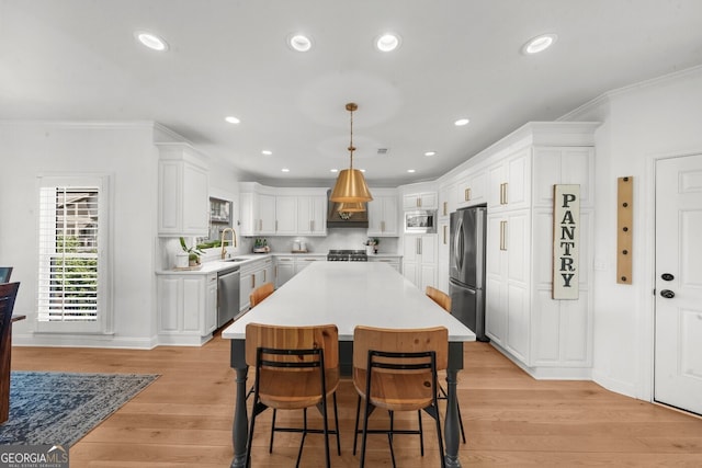 kitchen with light countertops, appliances with stainless steel finishes, a breakfast bar, and white cabinets