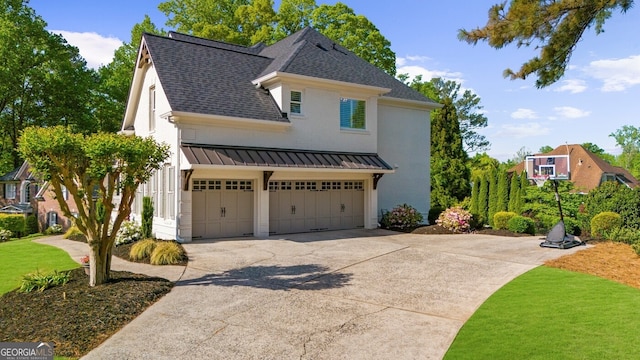 view of side of property with a standing seam roof, driveway, a garage, brick siding, and a shingled roof