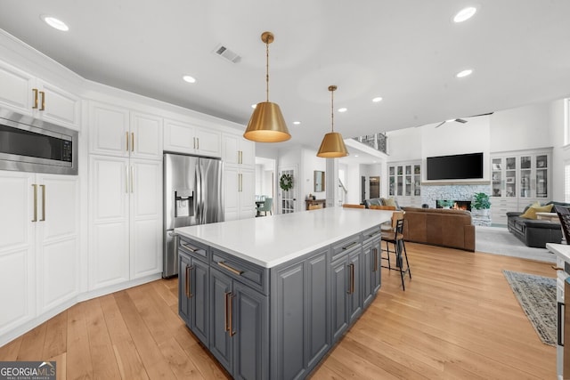 kitchen featuring gray cabinets, stainless steel appliances, white cabinets, visible vents, and a kitchen island