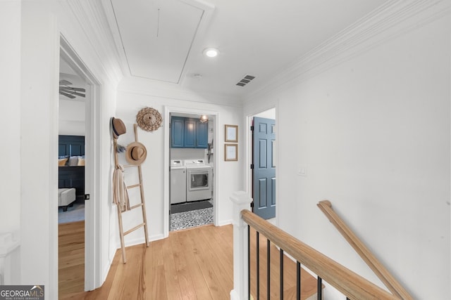 hall with an upstairs landing, attic access, light wood finished floors, washing machine and dryer, and visible vents