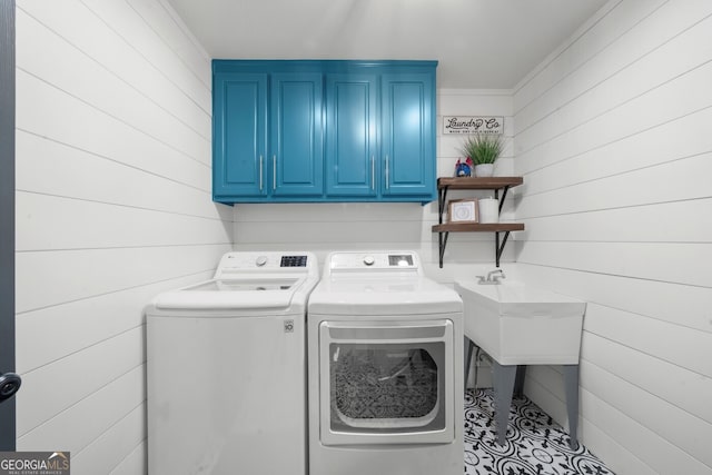 washroom featuring separate washer and dryer, cabinet space, and wooden walls