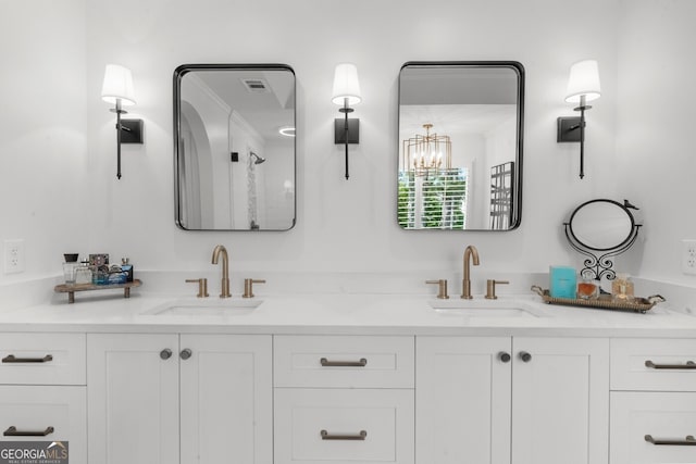 bathroom with a sink, a chandelier, and double vanity
