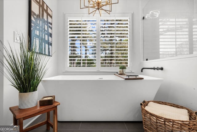 bathroom featuring a freestanding bath, a notable chandelier, and tile patterned flooring