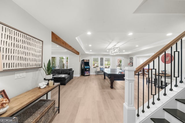 rec room featuring recessed lighting, light wood-style floors, a notable chandelier, and a tray ceiling