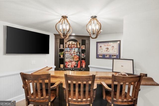 dining area featuring a wainscoted wall and a chandelier