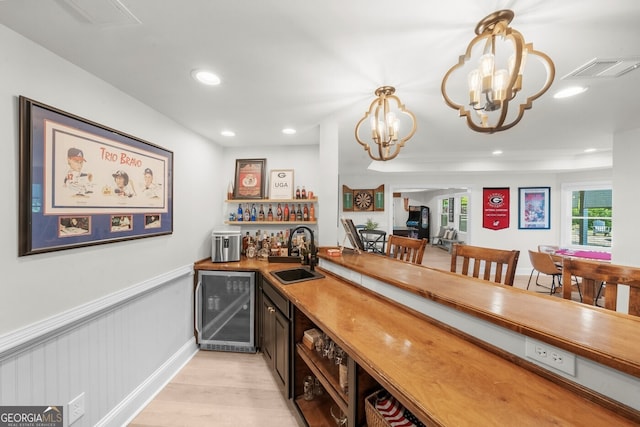 bar featuring light wood finished floors, wine cooler, a sink, visible vents, and a bar