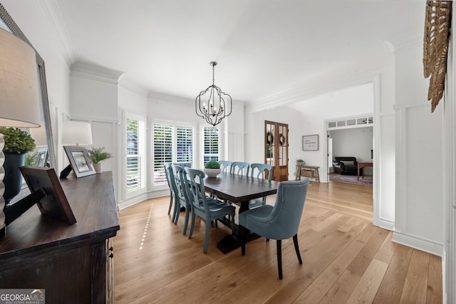 dining room with an inviting chandelier, crown molding, and light wood-style floors