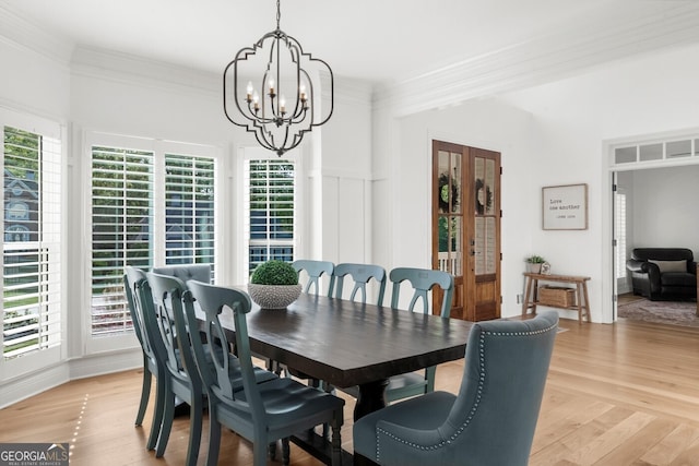 dining space featuring light wood finished floors, crown molding, and a notable chandelier