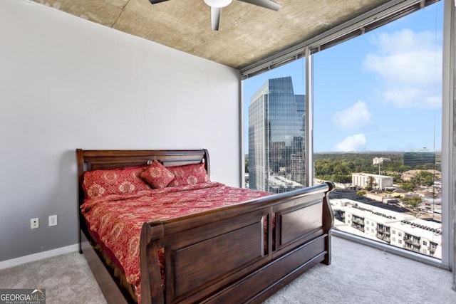 bedroom with carpet flooring, baseboards, a ceiling fan, floor to ceiling windows, and a view of city