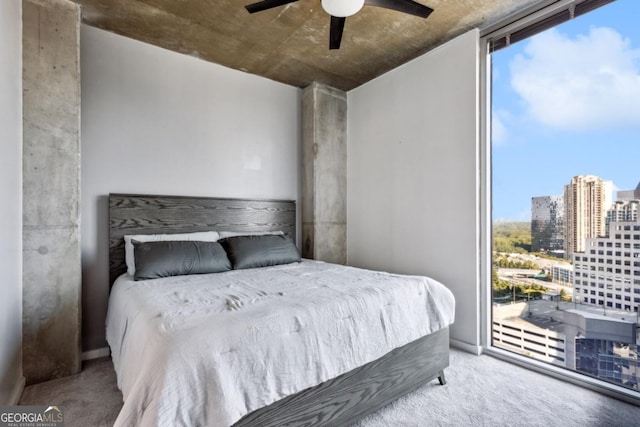 bedroom with a view of city, ceiling fan, a wall of windows, carpet flooring, and access to exterior