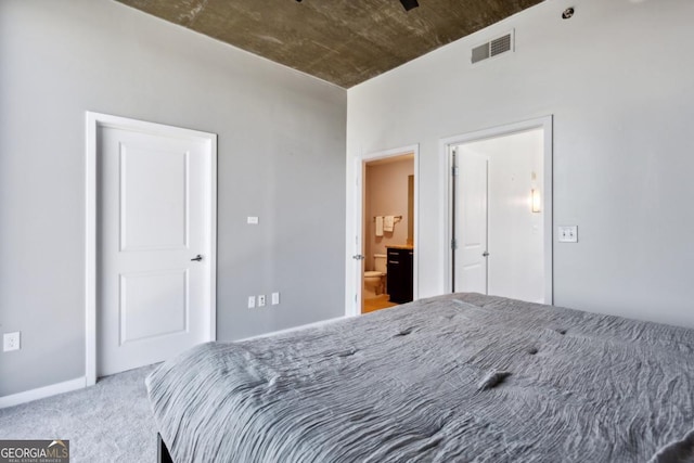 carpeted bedroom featuring ensuite bath and visible vents