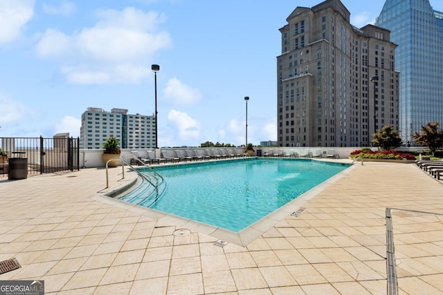 community pool with fence and a patio