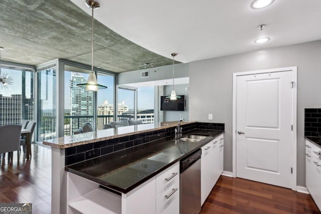 kitchen with a peninsula, stainless steel dishwasher, a sink, white cabinetry, and dark wood-type flooring