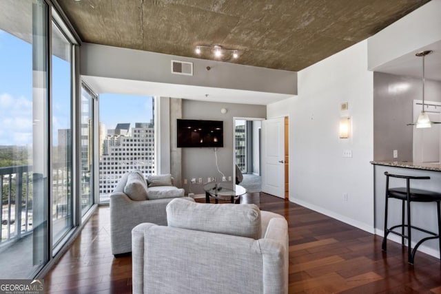 living area with dark wood finished floors, visible vents, and baseboards