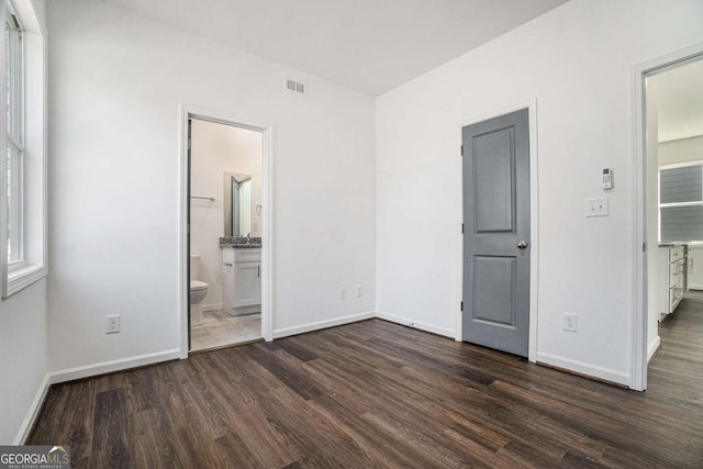 102 Dahlia Ave SW, Atlanta, GA 30314 - unfurnished bedroom with connected bathroom, baseboards, visible vents, and dark wood-style floors