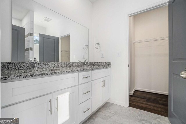 102 Dahlia Ave SW, Atlanta, GA 30314 - bathroom featuring a walk in closet, baseboards, a sink, and double vanity
