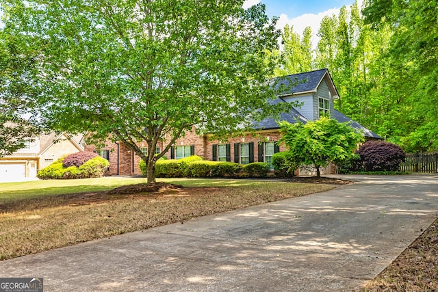 60 Fischer Trce, Newnan, GA 30265 - view of property hidden behind natural elements with fence, roof with shingles, concrete driveway, brick siding, and a front yard