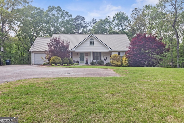 view of front of house featuring an attached garage, driveway, a front yard, and metal roof