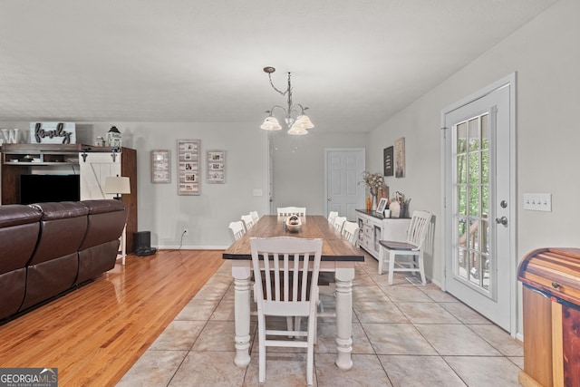 dining space with a chandelier, light wood-type flooring, and baseboards