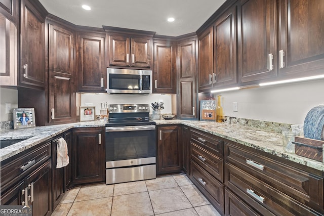 kitchen with light stone countertops, stainless steel appliances, and dark brown cabinetry