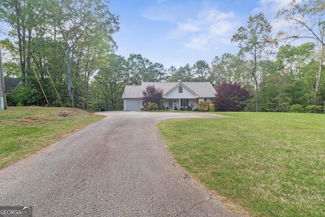 view of front of property featuring an attached garage, aphalt driveway, a front lawn, and metal roof