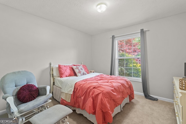 bedroom with light carpet, baseboards, and a textured ceiling