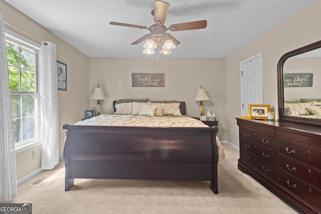 bedroom with light carpet, a ceiling fan, visible vents, and baseboards