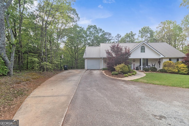 view of front of property with a porch, metal roof, an attached garage, a front yard, and aphalt driveway
