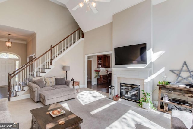 carpeted living area featuring baseboards, high vaulted ceiling, stairs, and ceiling fan