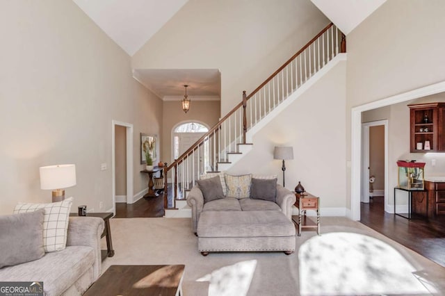 living area with baseboards, wood finished floors, high vaulted ceiling, and stairs