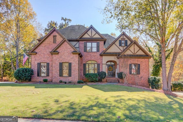tudor-style house with a front lawn, brick siding, and roof with shingles