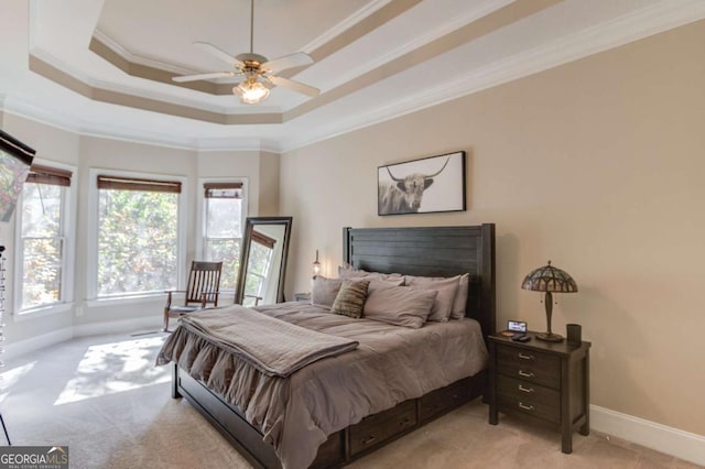 bedroom featuring light colored carpet, baseboards, ornamental molding, and a tray ceiling