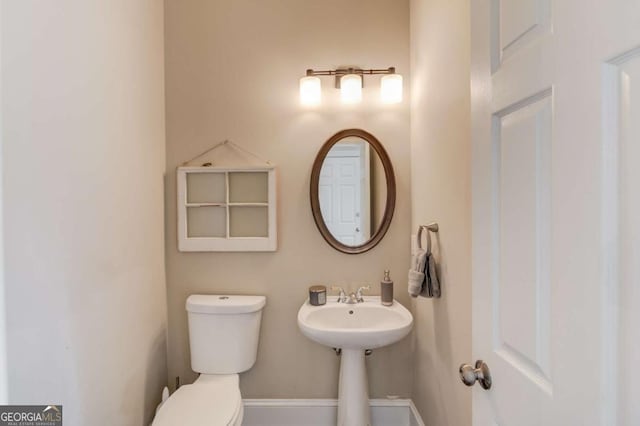 half bathroom featuring baseboards and toilet