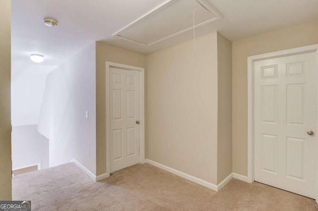 interior space featuring attic access, baseboards, and light carpet