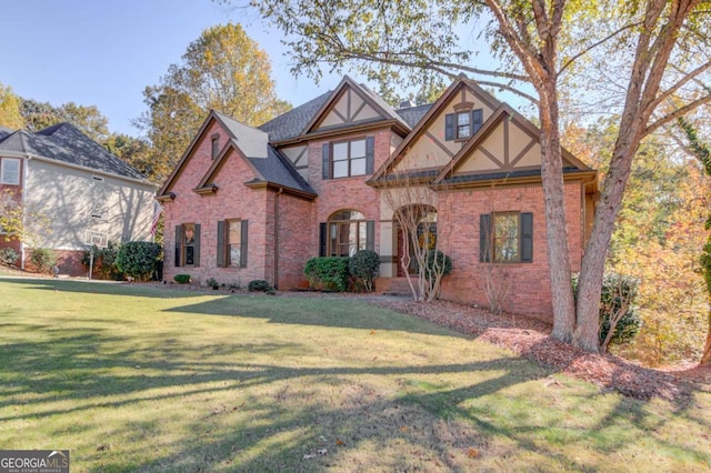 tudor-style house featuring a front lawn and brick siding